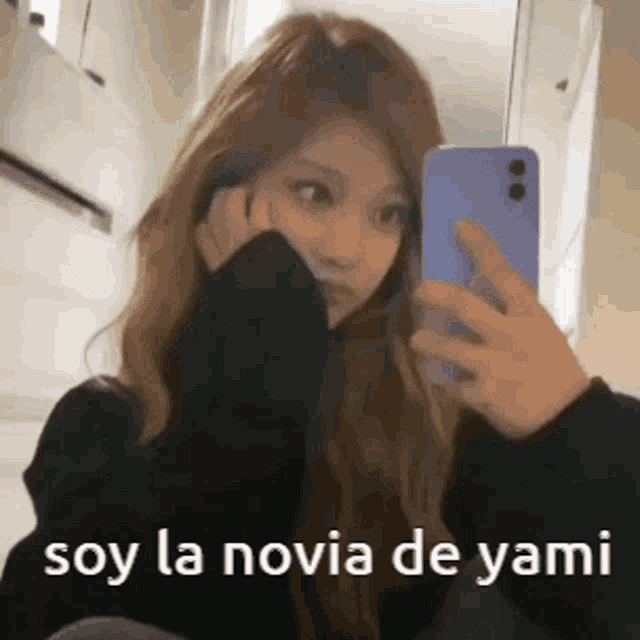 a woman is taking a picture of herself in a mirror with the words `` soy la novia de yami '' written below her .