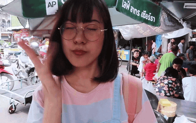 a woman wearing glasses stands under an umbrella that says ap on it