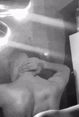 a man without a shirt is taking a selfie in front of a mirror .
