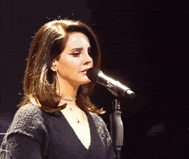 a woman singing into a microphone with a sweater on
