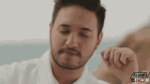 a man with a beard is wearing a white shirt and making a face .