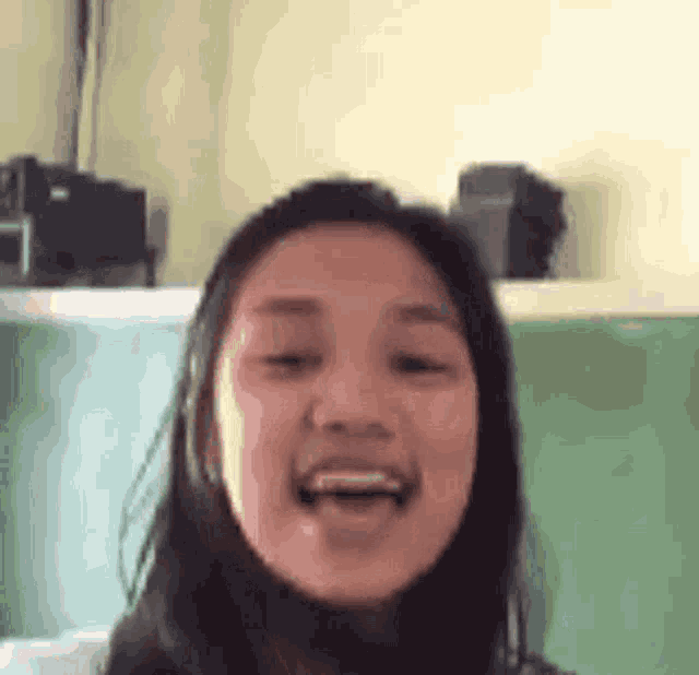 a young woman is making a funny face in front of a green board in a classroom .