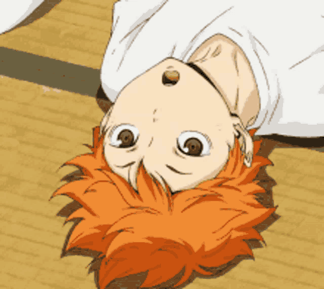 a boy with orange hair is laying upside down on the floor