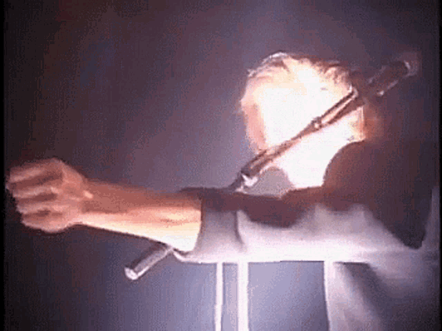 a man is singing into a microphone with his fist up