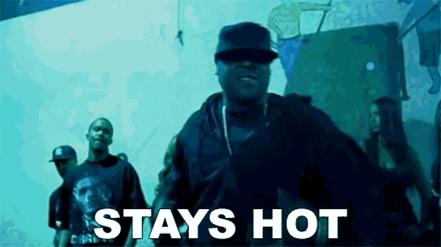 a group of men are standing in front of a wall with the words stays hot written on it