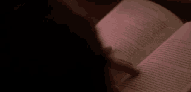 a person is reading a book with a pink light on the page