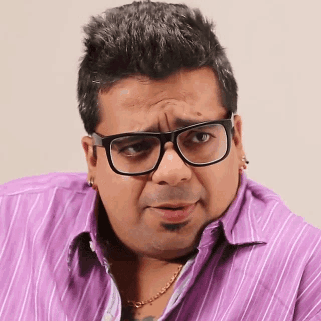 a man wearing glasses and a purple shirt is making a face