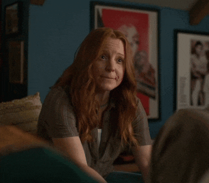 a woman with long red hair is sitting in front of a framed picture of a woman