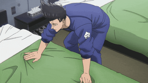 a man in a blue shirt is crawling on a bed with kleenex on the nightstand in the background