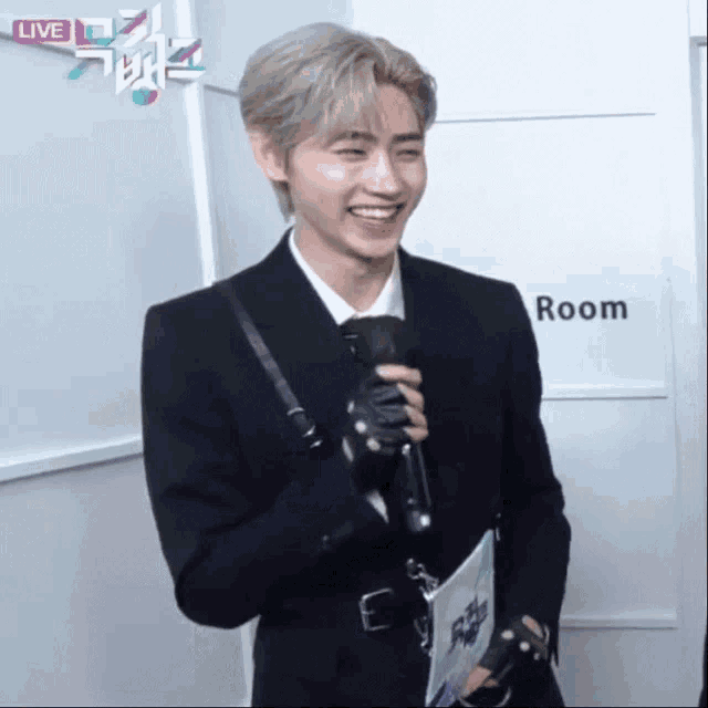 a man in a suit is smiling in front of a room sign