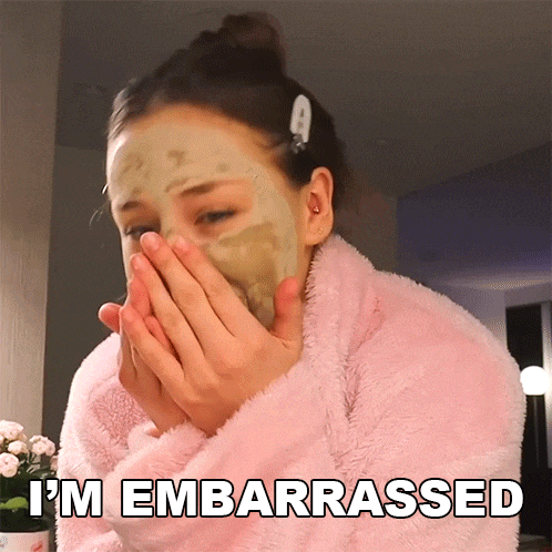 a woman with a mask on her face is covering her mouth with her hands and the words i 'm embarrassed are above her
