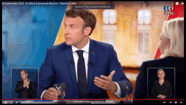 a man in a suit and tie is talking to a woman in a black shirt