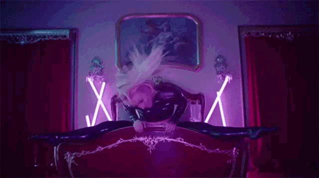 a woman is laying on a bed in a room with neon lights .