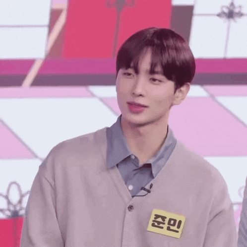 a young man wearing a sweater and a name tag with chinese writing on it .