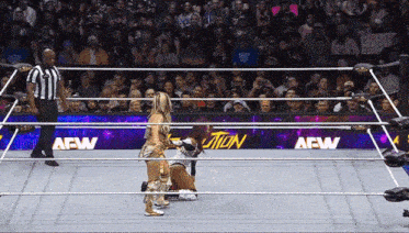 a woman in a wrestling ring with a crowd watching and a sign that says aew on it