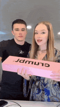 a man and a woman are holding a pink box that says ' jdmwr ' on it