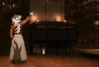 a man in a kimono is dancing on a stage in a dark room .
