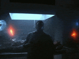 a person is standing in a dark room with a light coming out of the ceiling