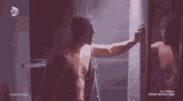 a shirtless man is standing in a shower .