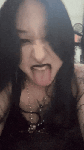 a woman sticking her tongue out while wearing a necklace