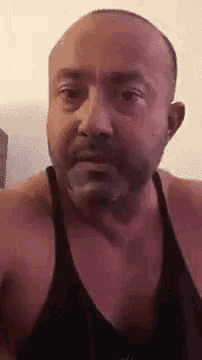 a bald man with a beard wearing a black tank top