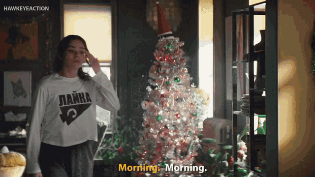 a woman standing in front of a christmas tree talking on a phone