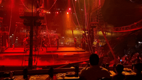 a man sits at a table in front of a stage with red lights