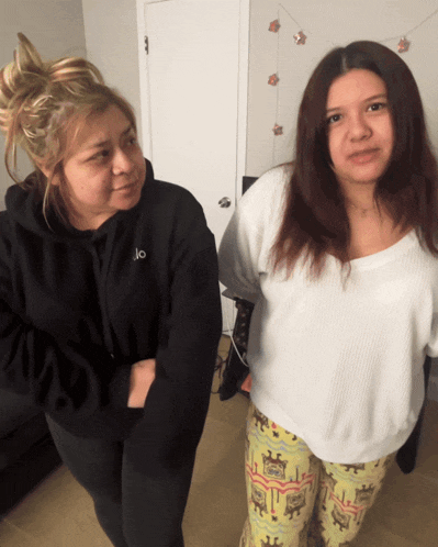 two women standing next to each other one wearing a black hoodie with the letter o on it