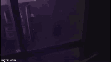 a person is standing in a dark room with a purple light behind them .