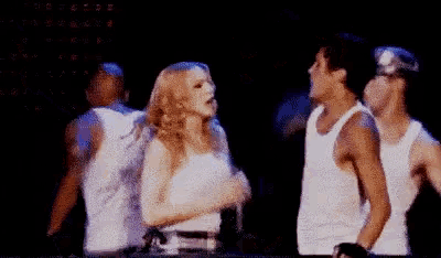 a group of people are dancing on a stage in front of a crowd .