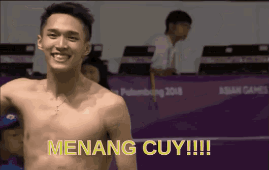 a shirtless man is smiling in front of a sign that says menang cuy