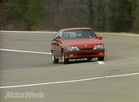 a red car is driving down a road with motorweek written in the corner