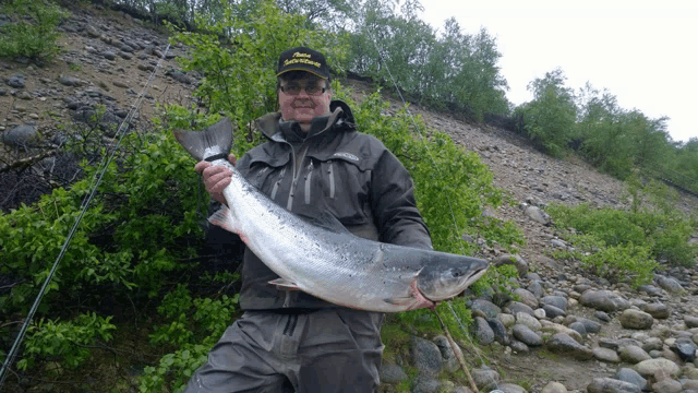 a man is holding a large fish and wearing a hat that says ' eagle fishing ' on it