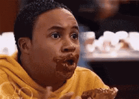 a man in a yellow hoodie is eating a piece of pizza with his mouth full .