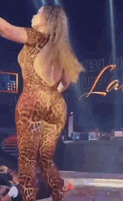 a woman in a leopard print jumpsuit is dancing on stage .