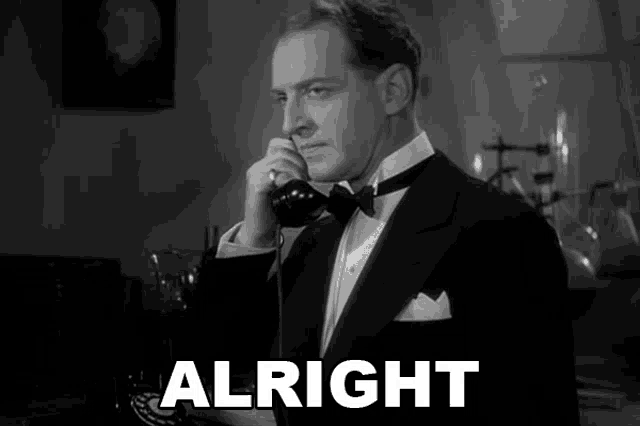 a man in a tuxedo is talking on a phone and the word alright is behind him
