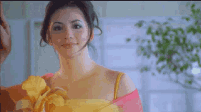 a woman in a yellow dress is looking at the camera .