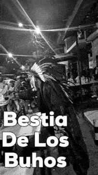 a black and white photo of a person wearing a feathered headdress with the caption " bestia de los buhos "