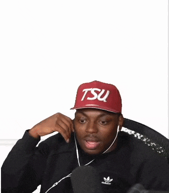 a man wearing a black hoodie and red and blue shorts is sitting down .