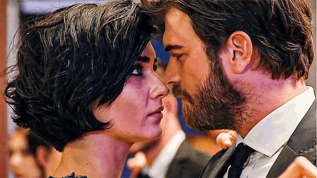 a man with a beard is kissing a woman on the nose