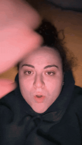 a woman wearing a black hoodie is making a face