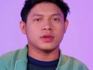 a close up of a man 's face with a purple background and a green jacket .