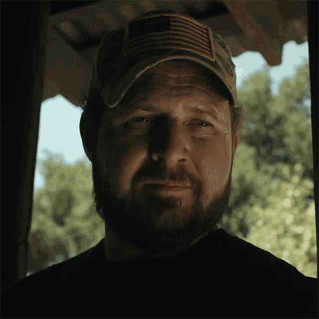 a man with a beard is wearing a hat with an american flag on it