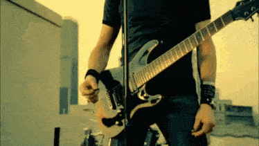 a man in a black shirt is playing a guitar in front of a microphone