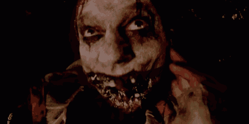 a close up of a scary clown 's face with blood coming out of his mouth .