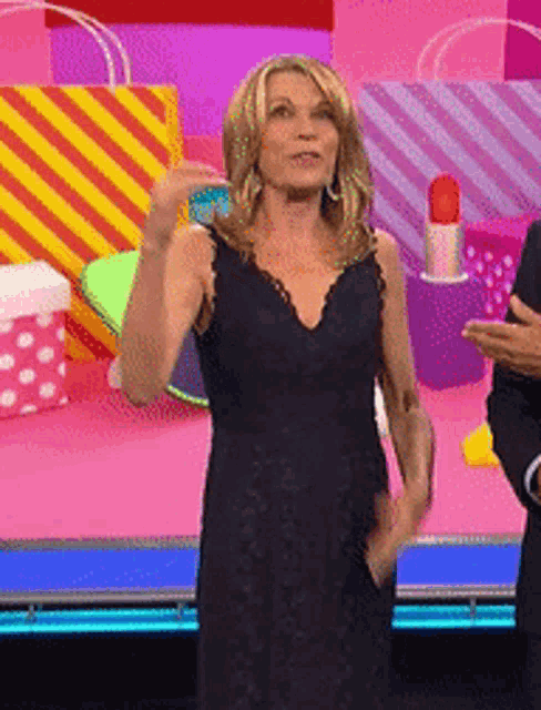 a woman in a black dress stands on a stage