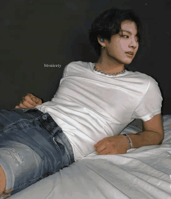 a man laying on a bed with a white shirt and blue shorts