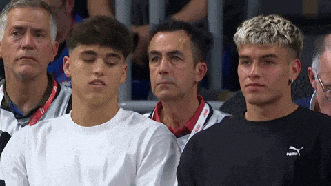 a group of young men are sitting in a stadium and one of them is wearing a puma sweatshirt