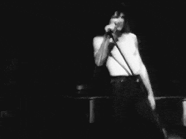 a man is singing into a microphone in a black and white photo .
