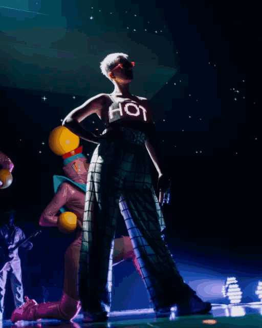 a woman wearing a shirt that says hot is standing on a stage
